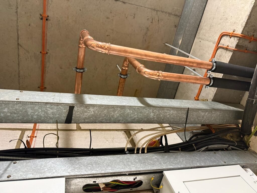 New copper pipework at ceiling level joining insulated pipe runs at Free Trade Wharf
