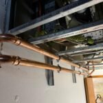 Two new copper water pipes run at high level along a wall at Free Trade Wharf