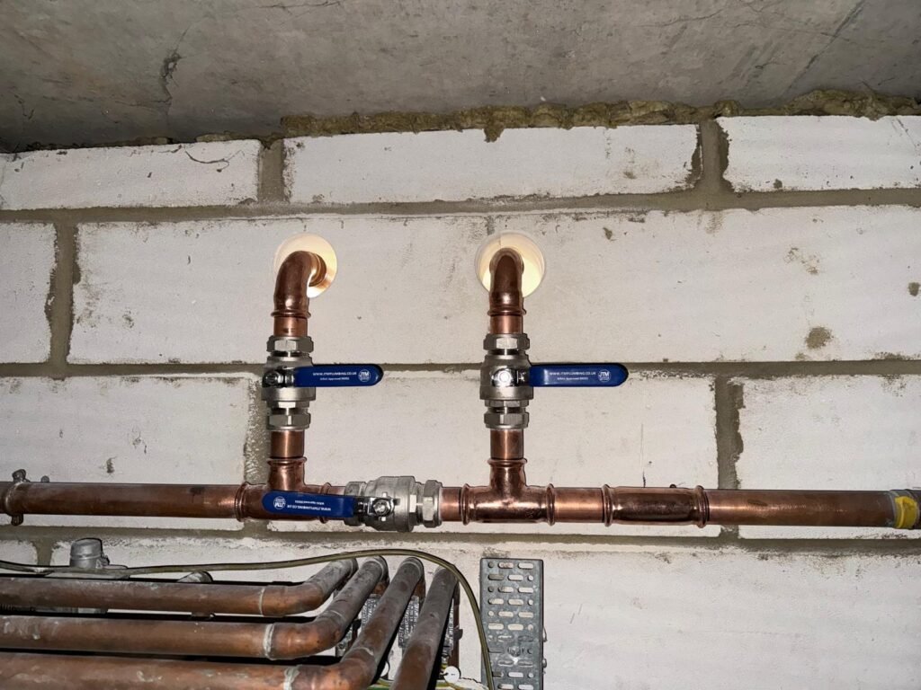 Isolation valves on new copper branch connections through a blockwork wall at Free Trade Wharf