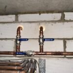 Isolation valves on new copper branch connections through a blockwork wall at Free Trade Wharf