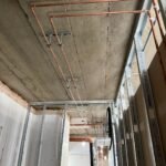 First fix copper pipework fixed to the concrete ceiling beside new stud partitions at Kestral House School