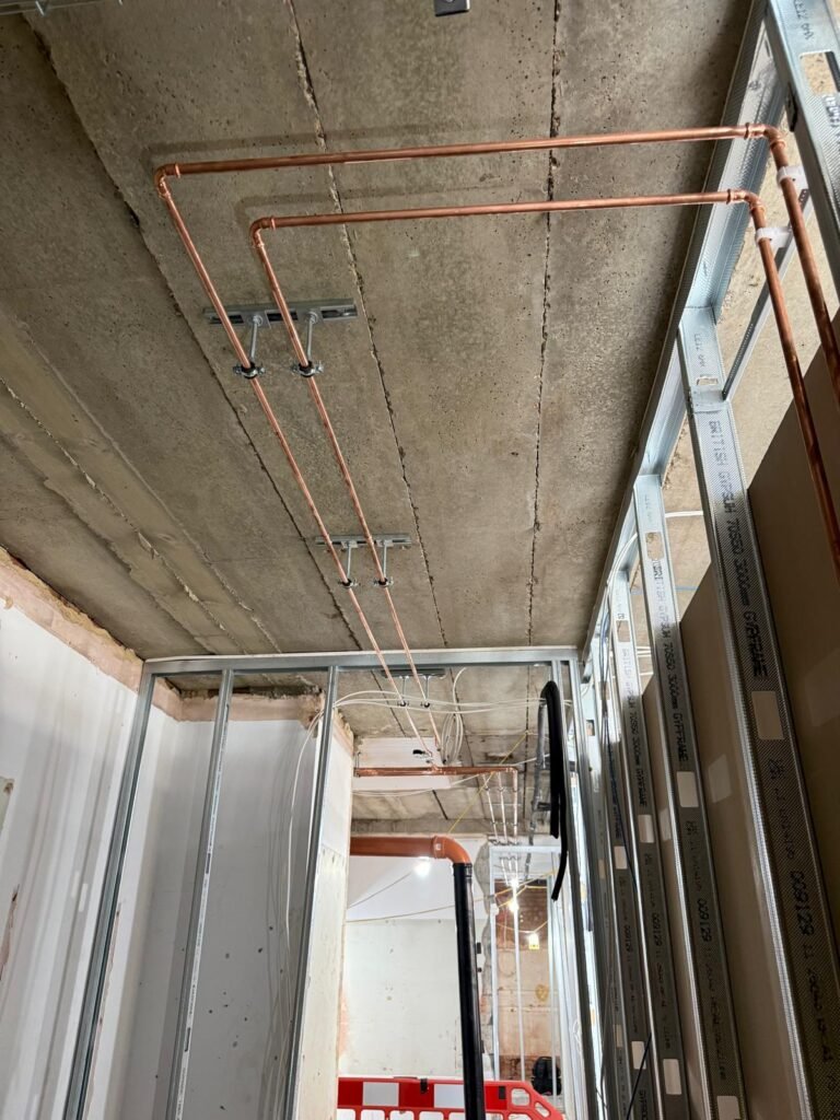 First fix copper pipework fixed to the concrete ceiling beside new stud partitions at Kestral House School