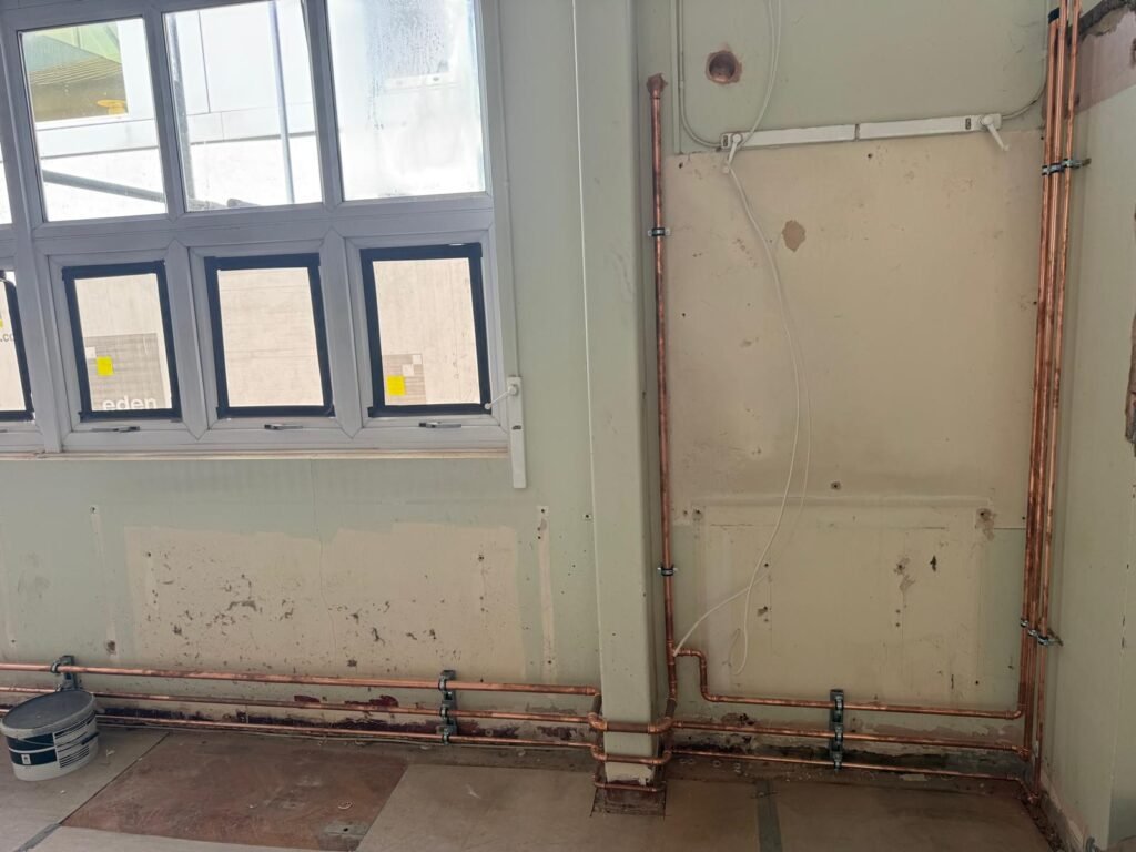 New copper water pipework run at low level along a wall at Kestral House School